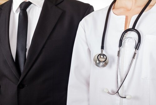 person in business suit standing next to person in doctor apparel 