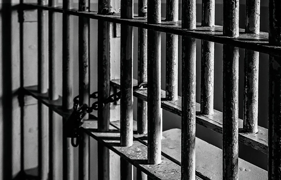 Black and white image of heavy iron bars within a prison.