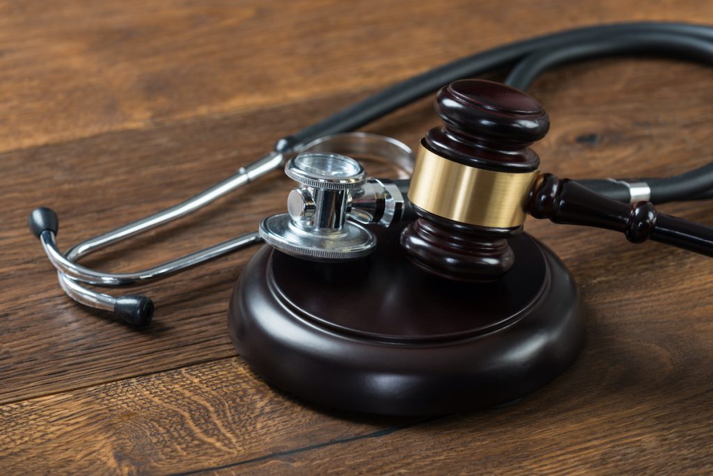 Closeup of gavel and stethoscope on table in courtroom