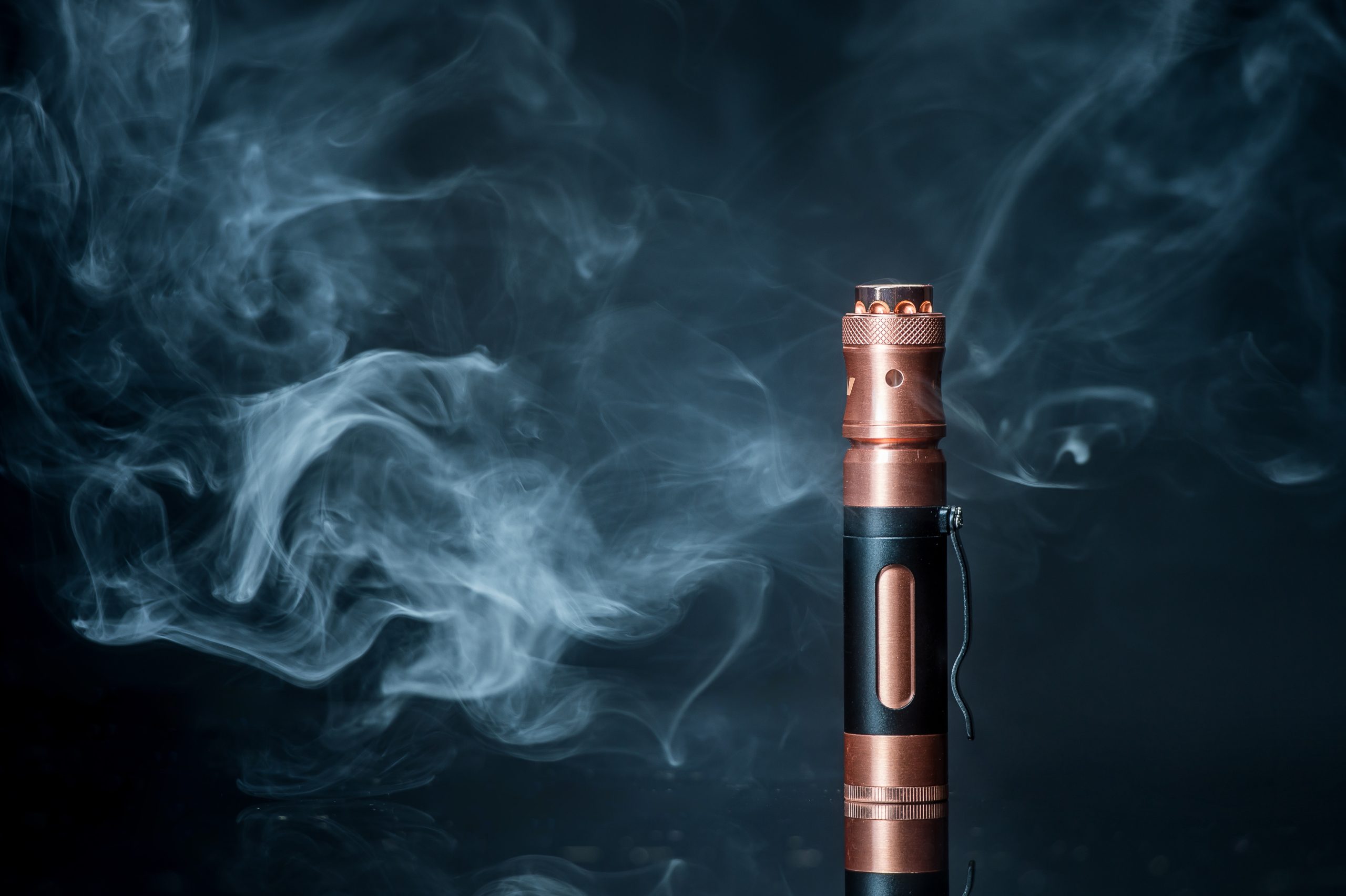 electronic cigarette placed vertically on surface with vapor clouds in the background
