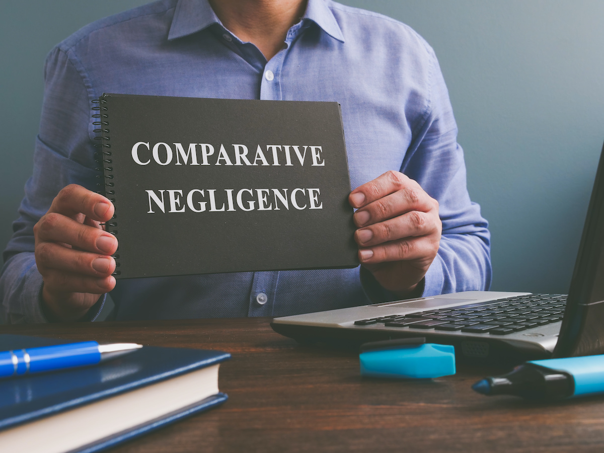 Man hold black notebook with cover titled Comparative Negligence