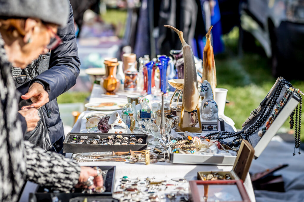 Items displayed on a table at a yard sale, with shoppers browsing options.