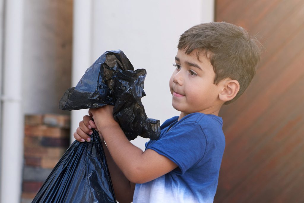 young child taking the trash out at a home.
