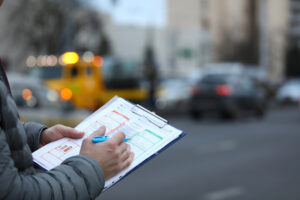 Male insurance agent filling report claim form on clipboard. Process after car accident.