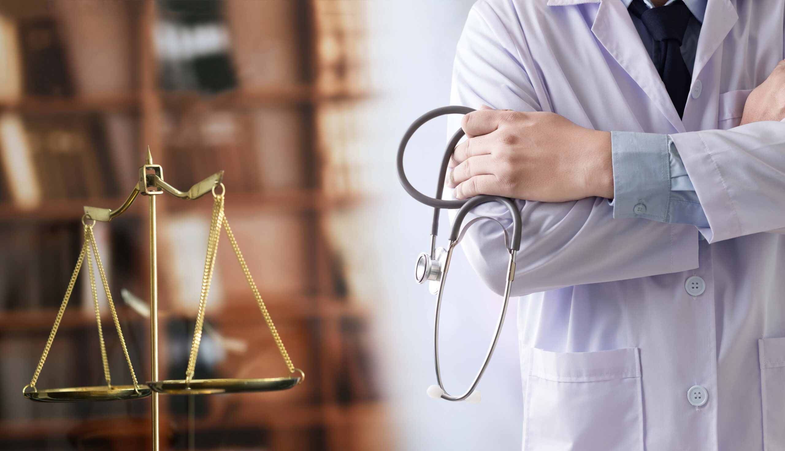 Doctor holding a stethoscope standing next to the Scales of Justice