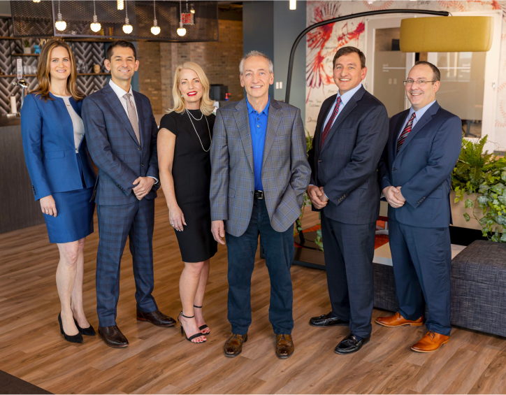 Attorneys standing and smiling at the camera in the office reception area.