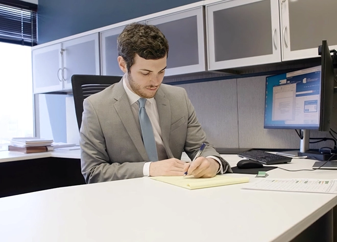 Nathan sitting at his desk writing down notes on a pad of paper