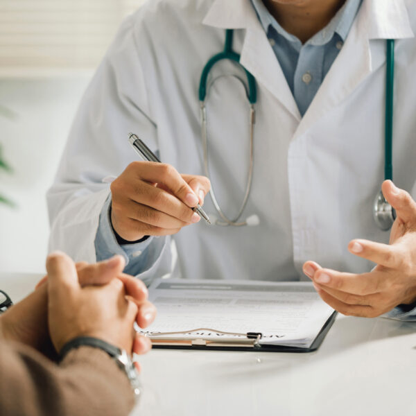 Doctor sitting down with patient in his office.