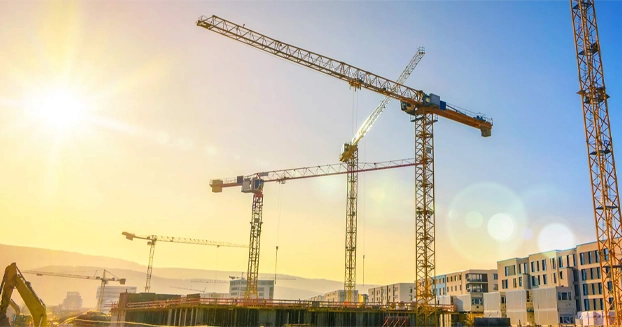 sunrise over a construction site with multiple cranes.