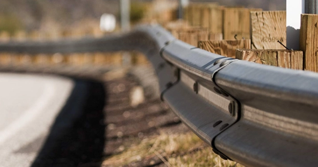 close up of a highway guard rail with the highway blurred in the background.