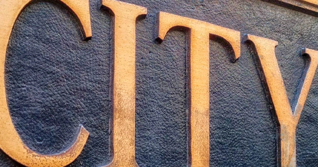 Bronzed words of CITY on a government building.