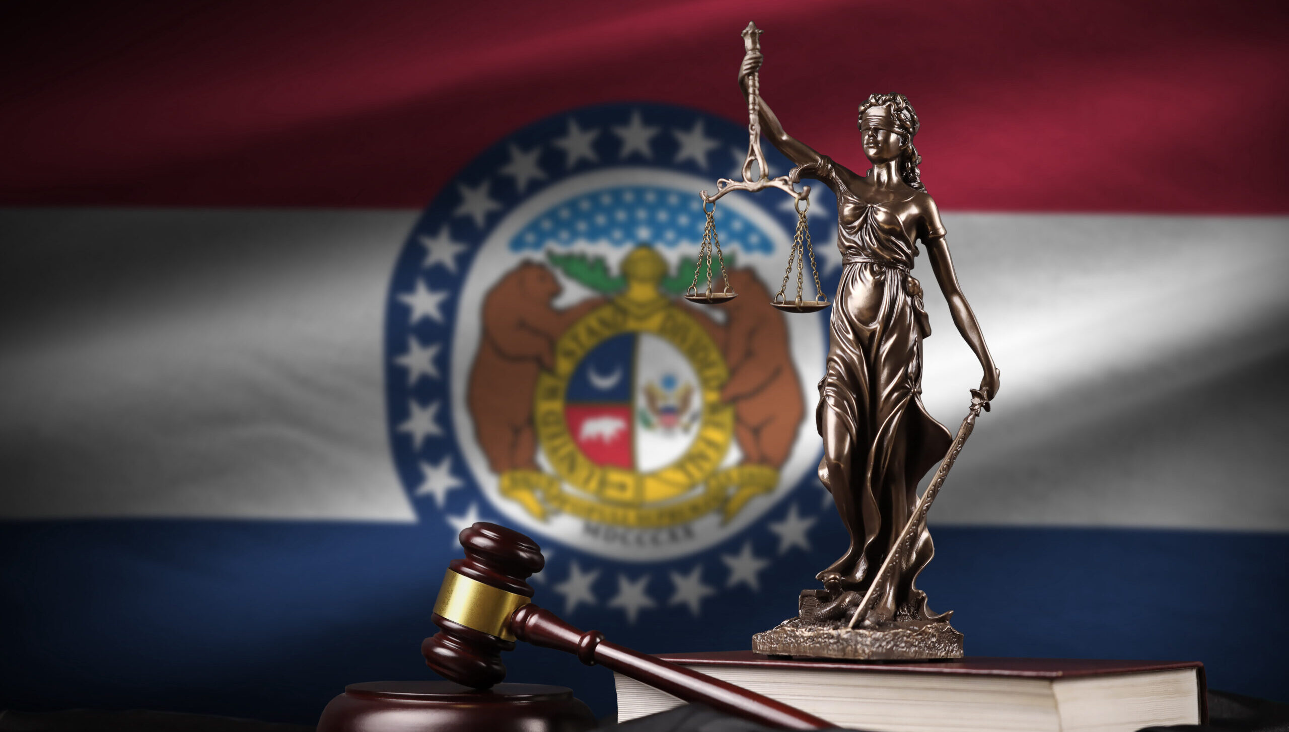 Missouri US state flag with statue of lady justice, constitution and judge hammer on black drapery.