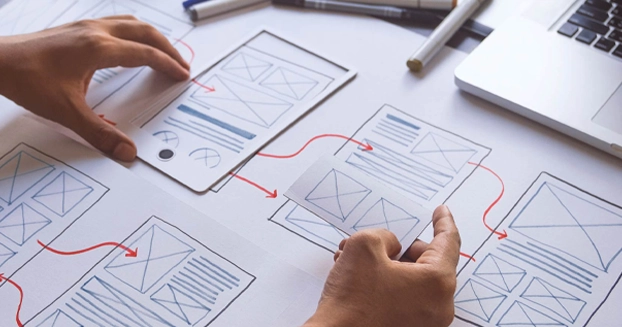 person wireframing a website with paper cut outs.