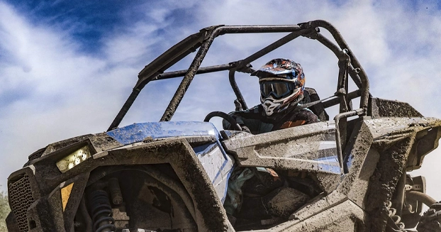 person driving a dirty, blue UTV.