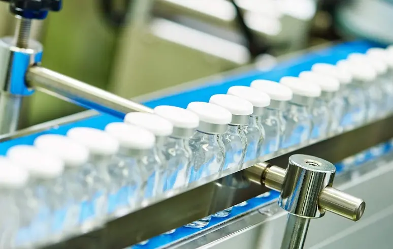 A bunch of drug containers on a conveyor belt.