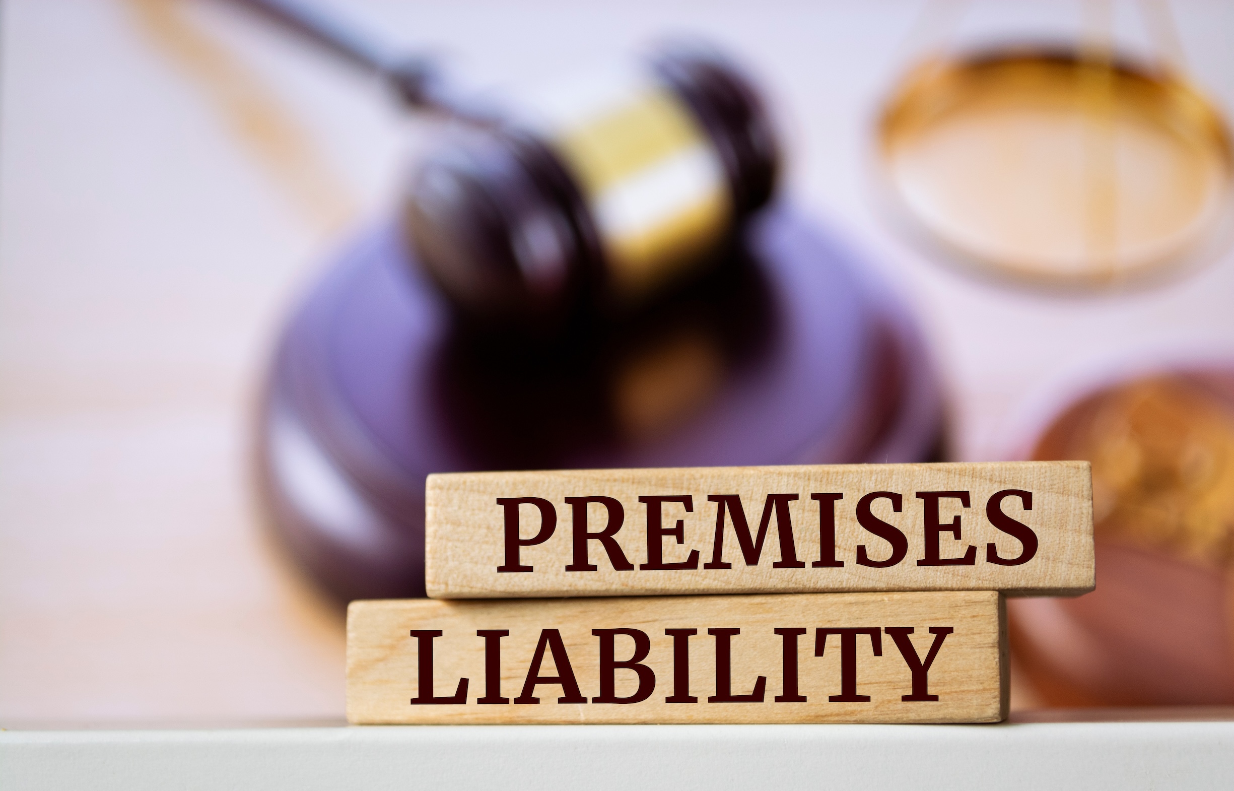 Wooden blocks with words 'Premises liability' with a judge's gavel and scales in the background.