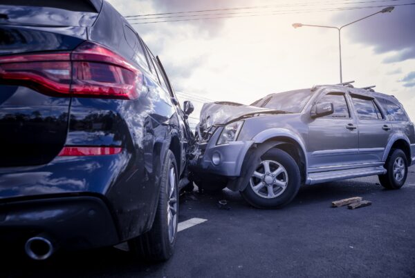 A newer black SUV and older silver SUV involved in a forward collision on the road.