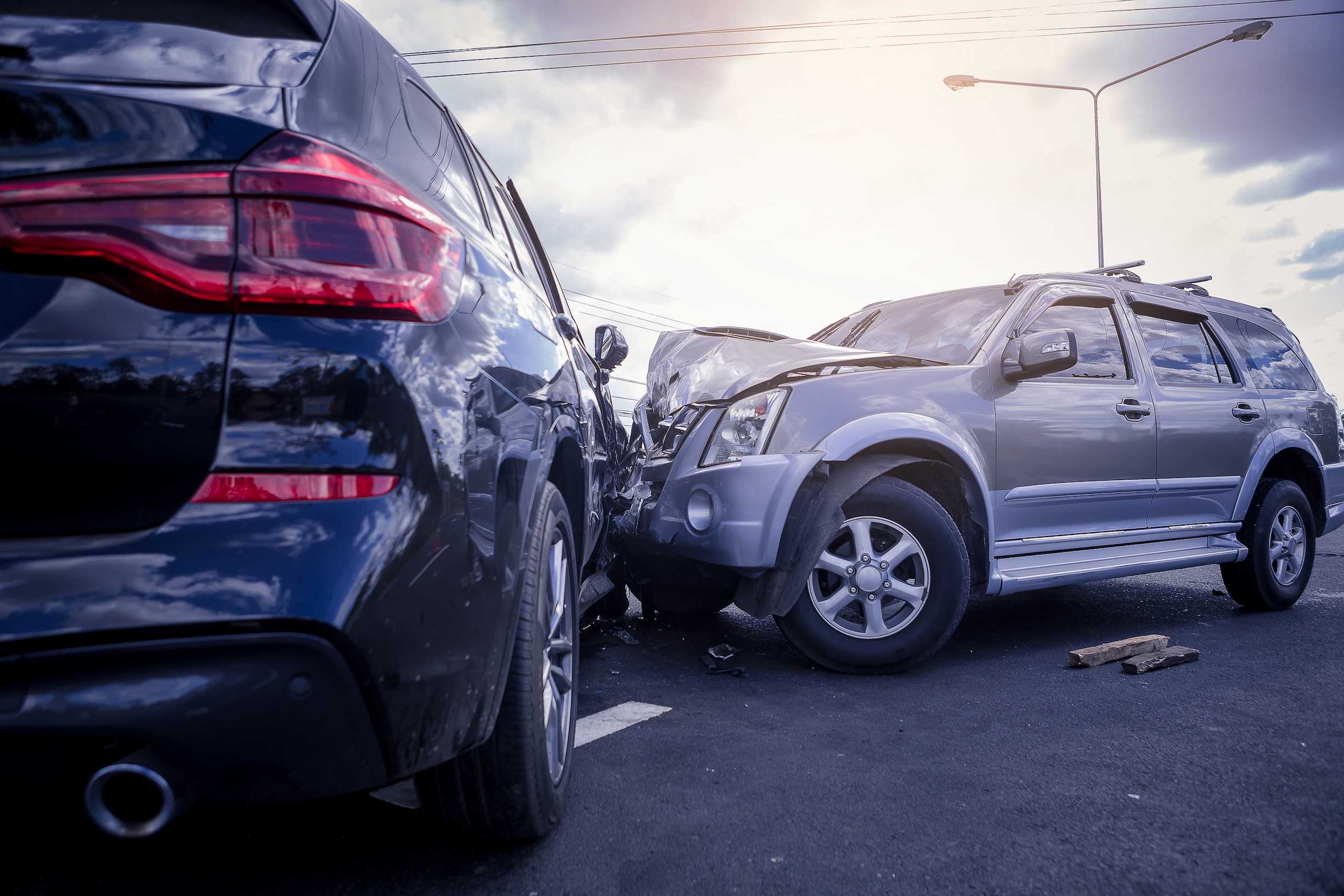 A newer black SUV and older silver SUV involved in a forward collision on the road.