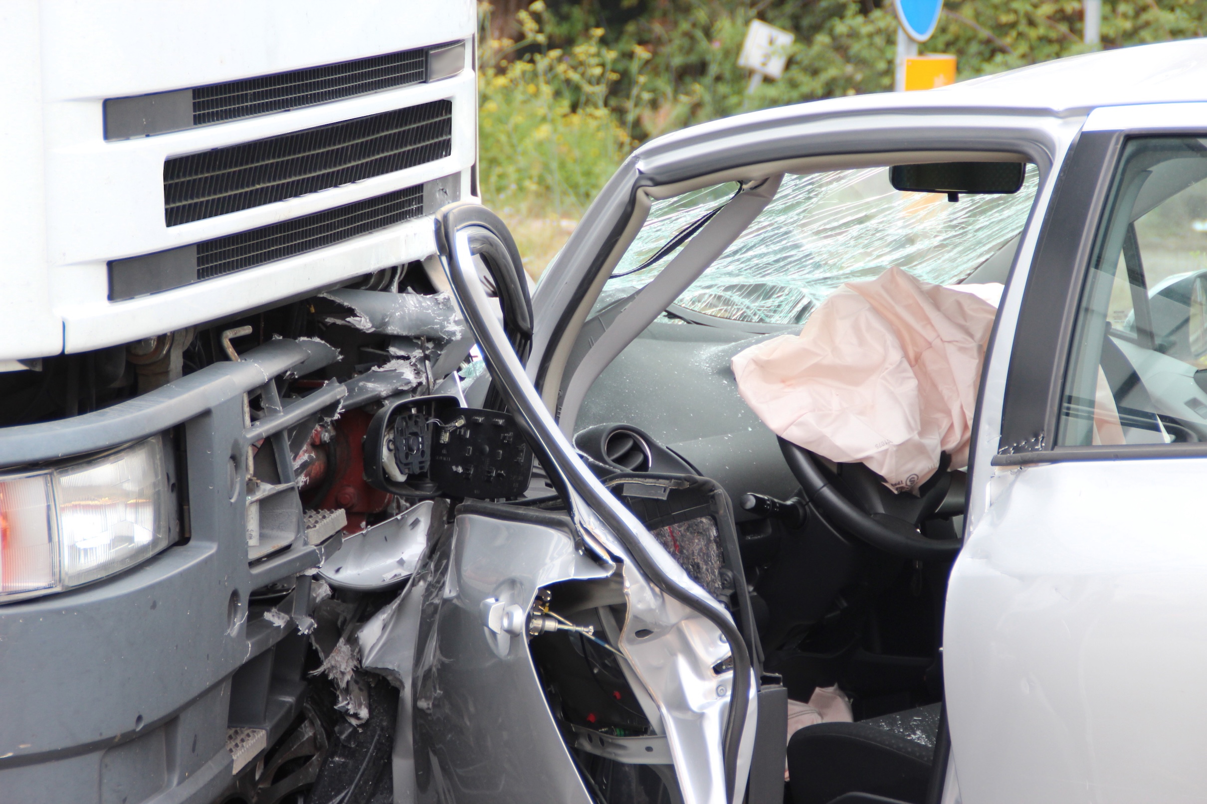 View of deployed airbag in a passenger vehicle after a head-on collision with a large truck.