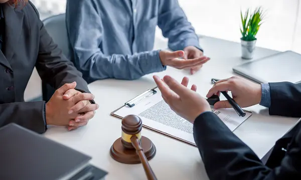 A legal professional discussing details of a business litigation case with two clients.