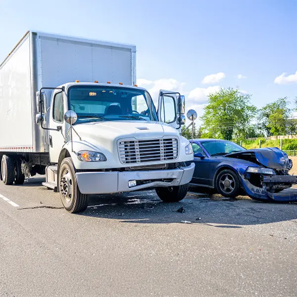 A white commercial box truck stopped on the road next to a wrecked passenger vehicle after both were involved in a collision.