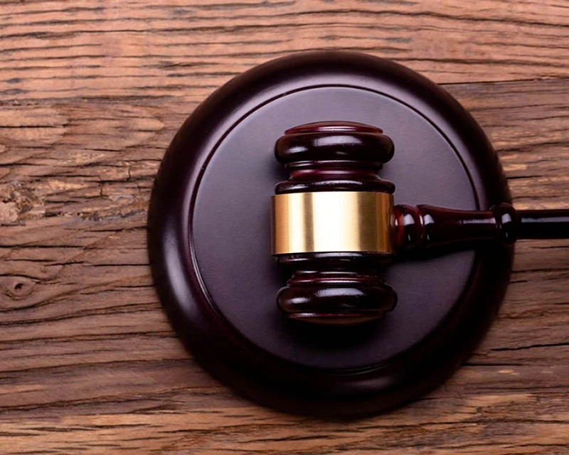 A judge's gavel laying on its side on a textured wood surface.