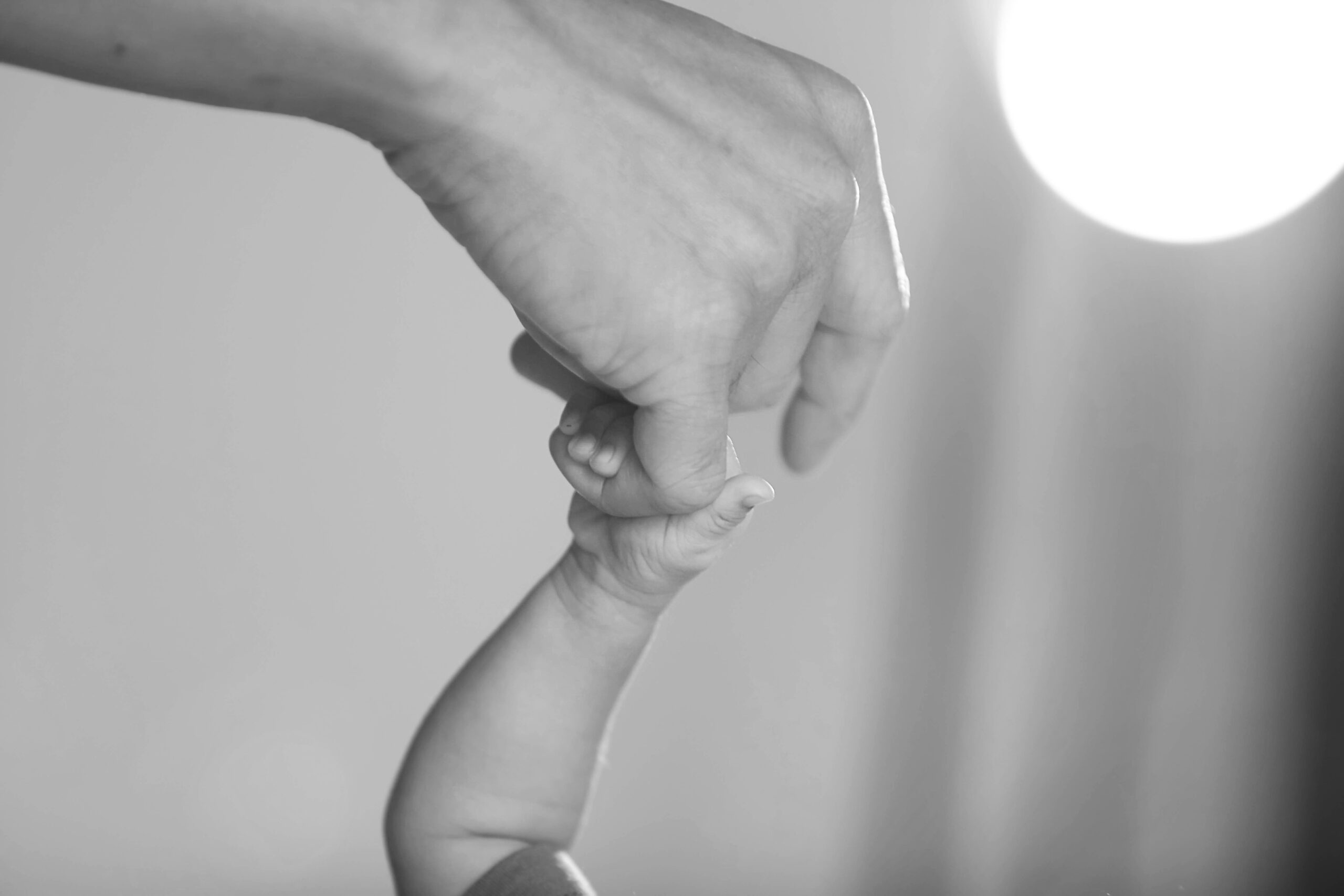 Newborn baby's hand holding finger of mother.
