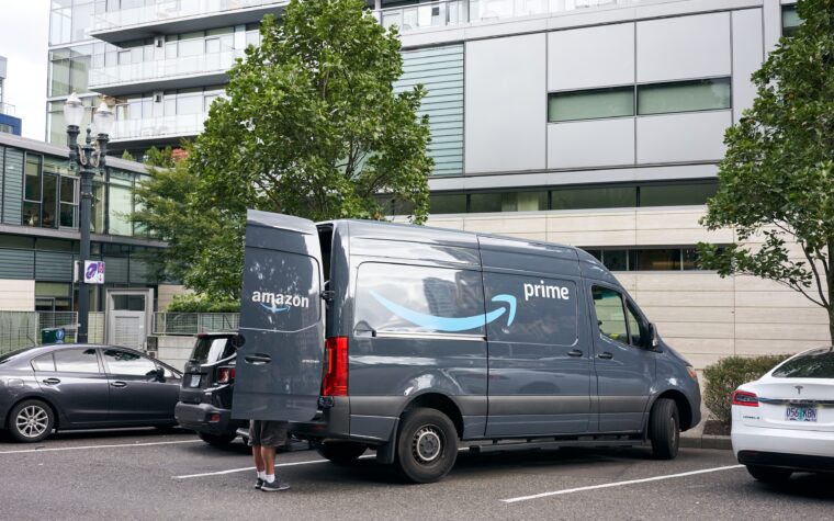 An Amazon Prime delivery van is being unloaded in a residential parking lot.